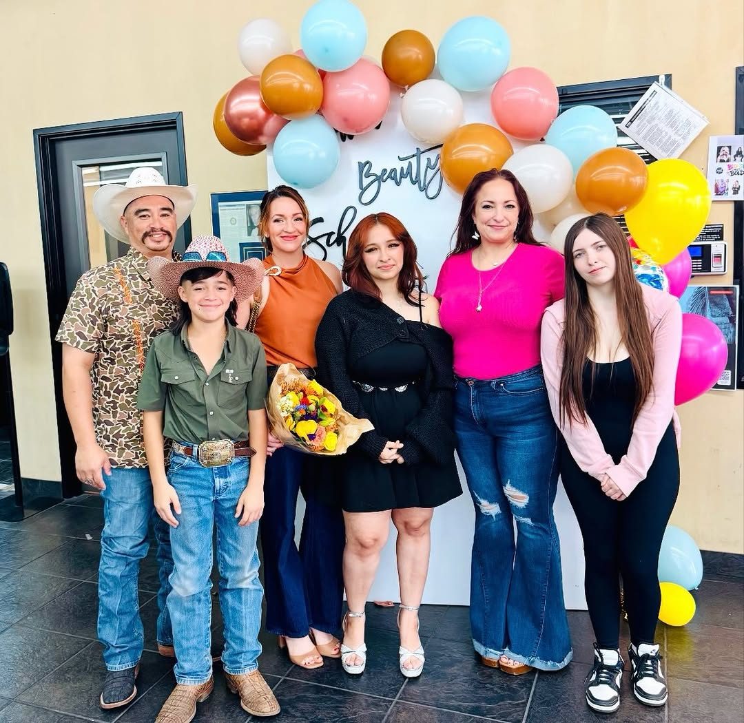 A graduating class and their instructors in front of a Baldwin Beauty Schools balloon backdrop